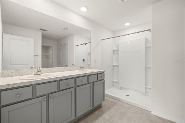 bathroom with tile patterned floors, walk in shower, and vanity