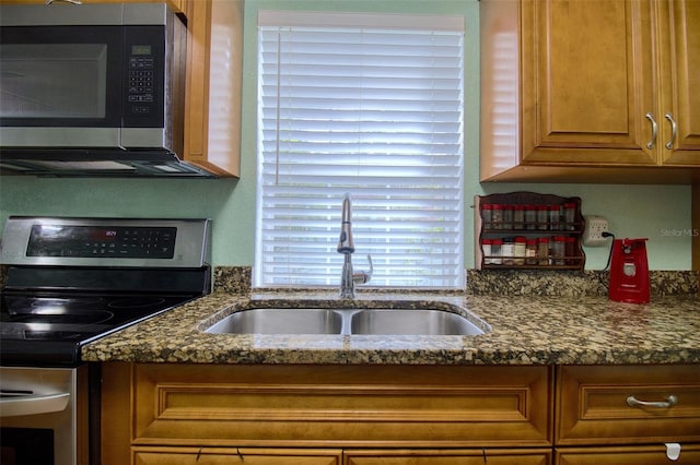 kitchen featuring appliances with stainless steel finishes, sink, and dark stone counters