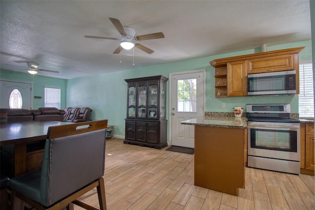 kitchen featuring a textured ceiling, light hardwood / wood-style flooring, stainless steel appliances, and ceiling fan