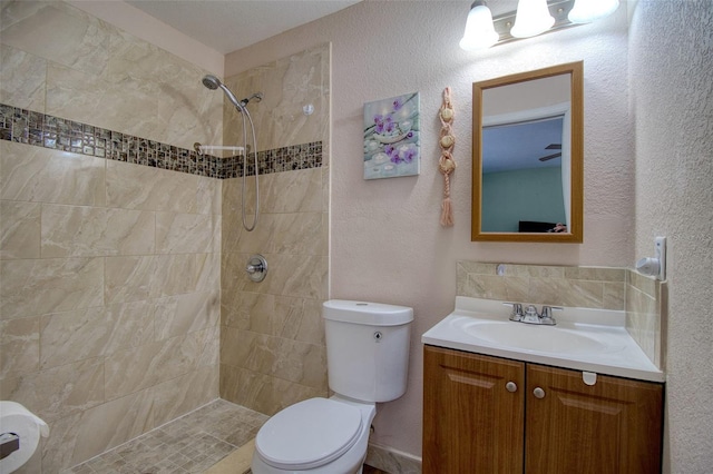 bathroom featuring tiled shower, toilet, and vanity