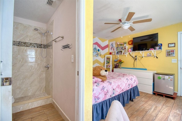 bedroom featuring a textured ceiling, ceiling fan, and stainless steel fridge