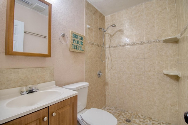 bathroom with tiled shower, toilet, and vanity