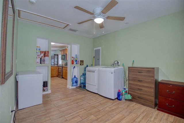 laundry area featuring light wood-type flooring, ceiling fan, washing machine and clothes dryer, and a textured ceiling