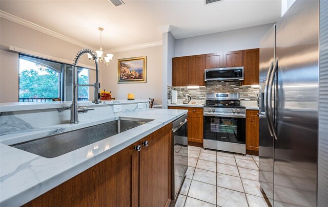 kitchen featuring decorative light fixtures, a notable chandelier, tasteful backsplash, stainless steel appliances, and sink