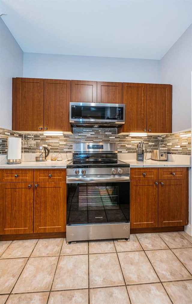 kitchen with appliances with stainless steel finishes, backsplash, and light tile patterned flooring