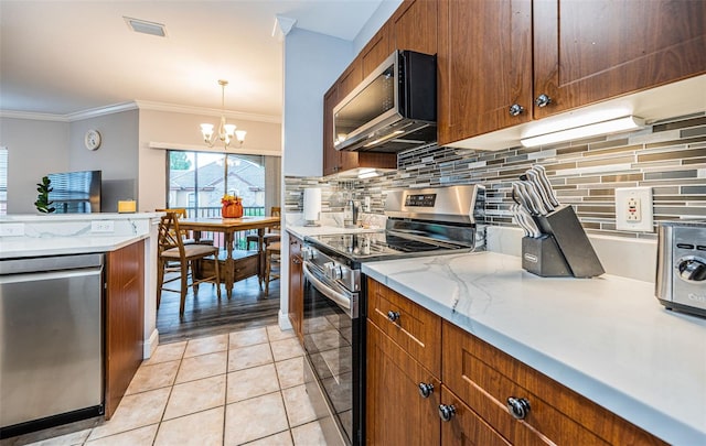 kitchen with an inviting chandelier, appliances with stainless steel finishes, light tile patterned flooring, pendant lighting, and ornamental molding