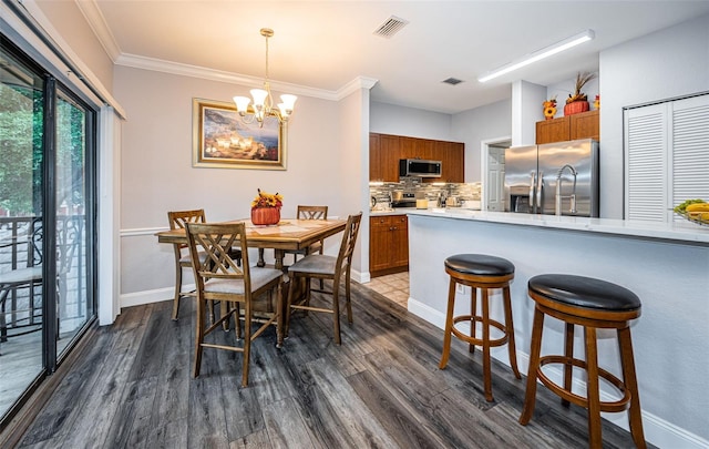 dining area featuring crown molding, dark hardwood / wood-style flooring, and a notable chandelier