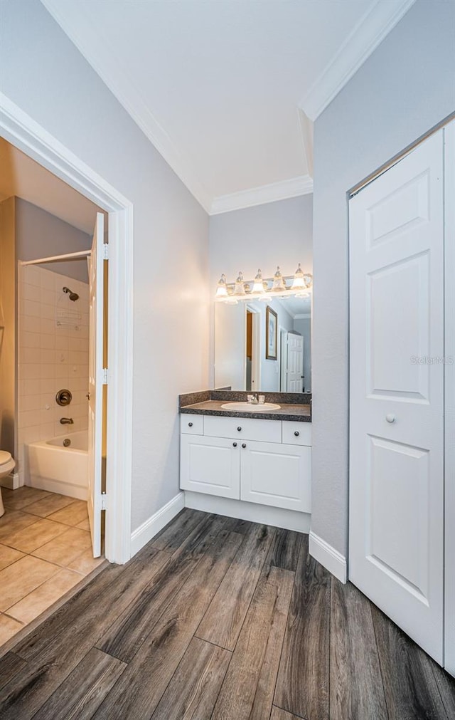 full bathroom featuring vanity, tiled shower / bath, wood-type flooring, and toilet