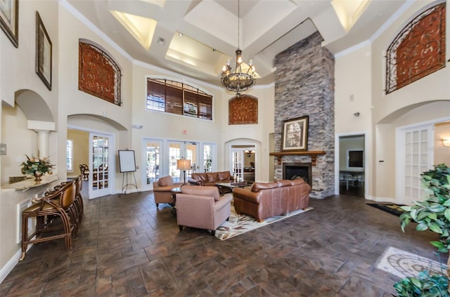 living room with a high ceiling, french doors, a chandelier, and a stone fireplace