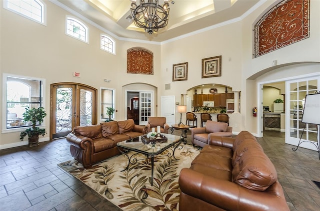 living room featuring crown molding, a high ceiling, a chandelier, and french doors