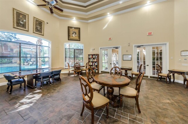 dining space with a high ceiling, ceiling fan, ornamental molding, and french doors