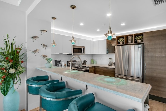 kitchen featuring light countertops, open shelves, backsplash, a peninsula, and appliances with stainless steel finishes