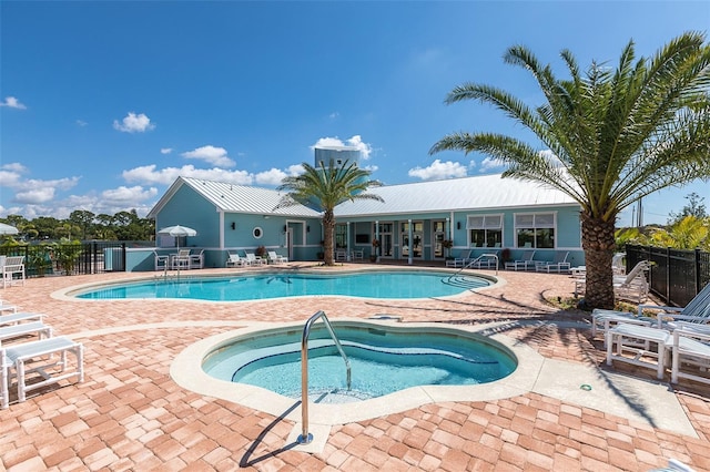 pool with fence, a patio area, and a hot tub