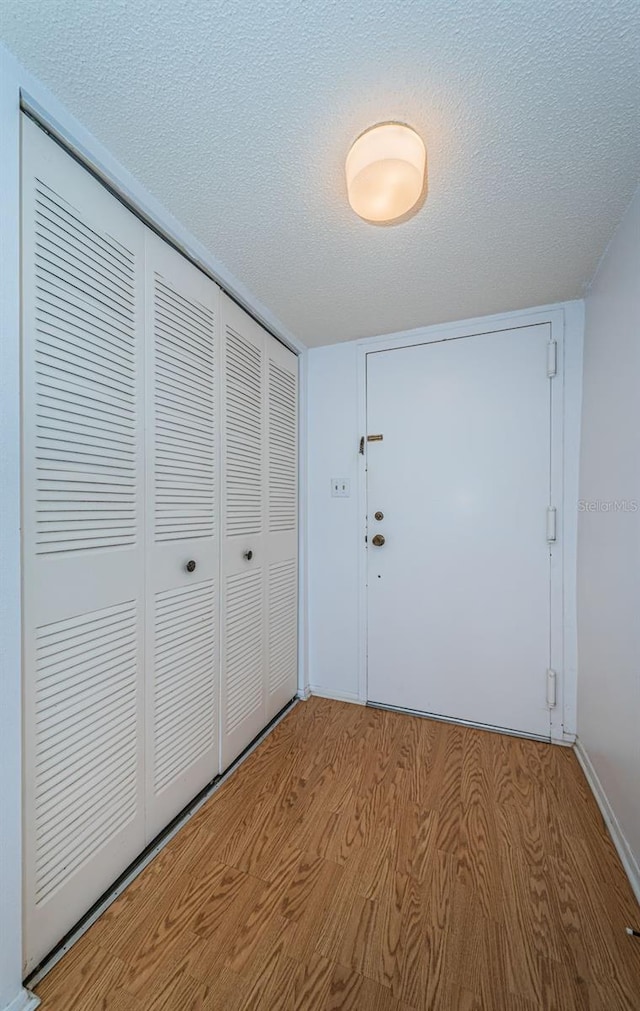 unfurnished bedroom featuring a closet, light hardwood / wood-style floors, and a textured ceiling