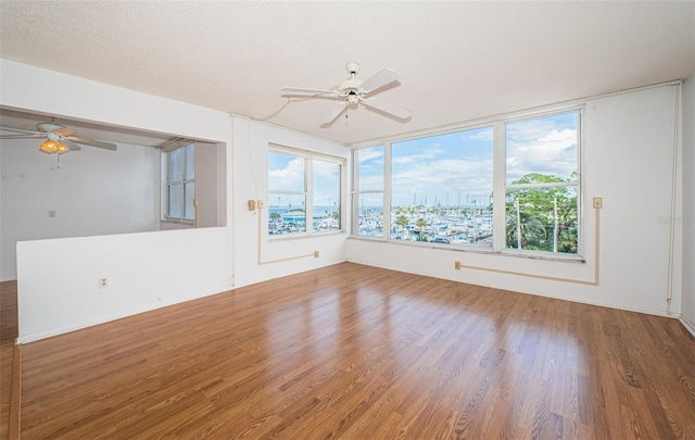 unfurnished room featuring plenty of natural light, a textured ceiling, hardwood / wood-style flooring, and ceiling fan