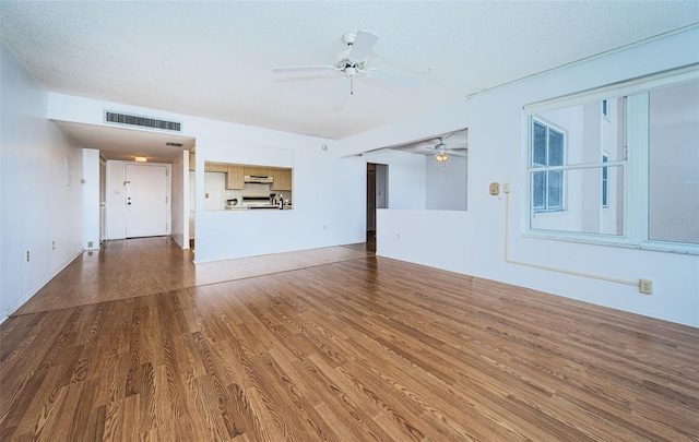 unfurnished living room featuring a textured ceiling, hardwood / wood-style floors, and ceiling fan