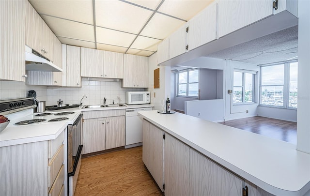 kitchen with backsplash, white appliances, light hardwood / wood-style floors, sink, and a drop ceiling