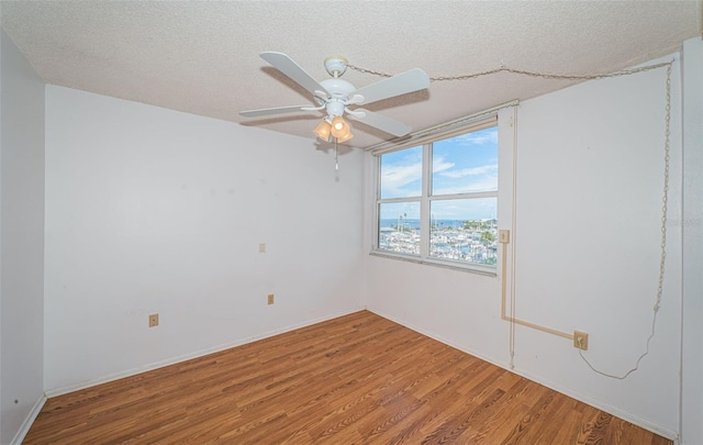 empty room with a textured ceiling, ceiling fan, and hardwood / wood-style floors