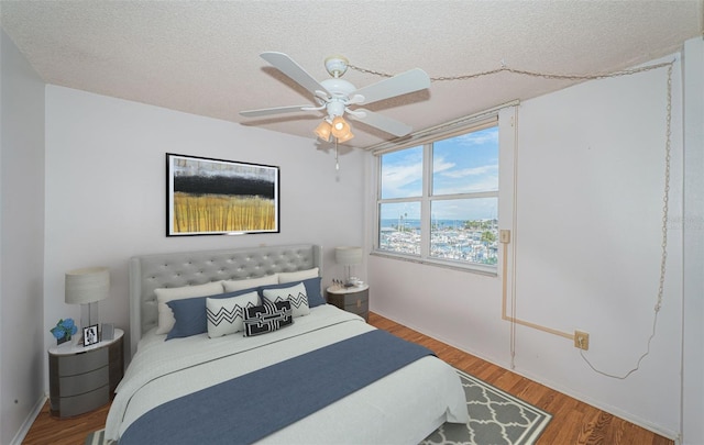 bedroom with a textured ceiling, ceiling fan, and wood-type flooring