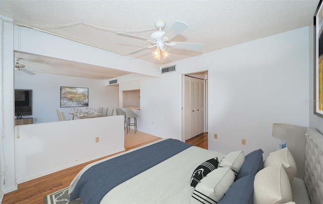 bedroom with a textured ceiling, a closet, ceiling fan, and hardwood / wood-style floors