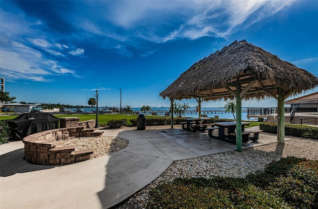 view of patio / terrace featuring an outdoor fire pit, a water view, and a gazebo