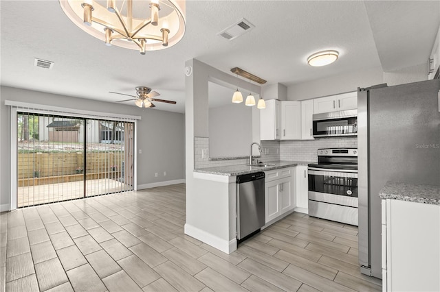 kitchen featuring stainless steel appliances, white cabinetry, sink, and pendant lighting