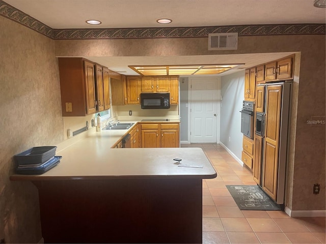 kitchen featuring kitchen peninsula, light tile patterned floors, sink, and black appliances