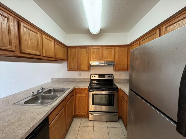 kitchen with appliances with stainless steel finishes, a textured ceiling, sink, and light tile patterned flooring