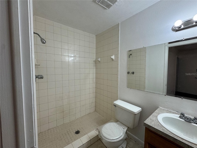 bathroom with toilet, a tile shower, a textured ceiling, and vanity