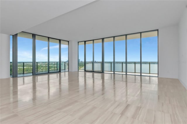 unfurnished room featuring plenty of natural light, floor to ceiling windows, and light hardwood / wood-style floors