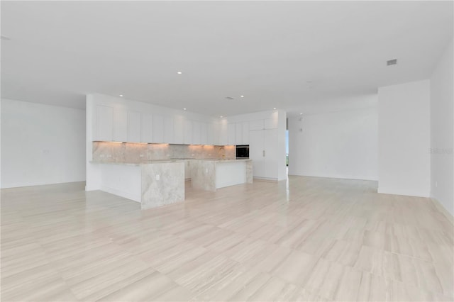 kitchen with light wood-type flooring, white cabinetry, backsplash, and sink