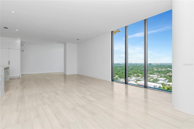 unfurnished living room featuring floor to ceiling windows and light hardwood / wood-style floors