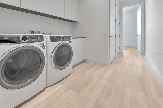 clothes washing area with cabinets and separate washer and dryer