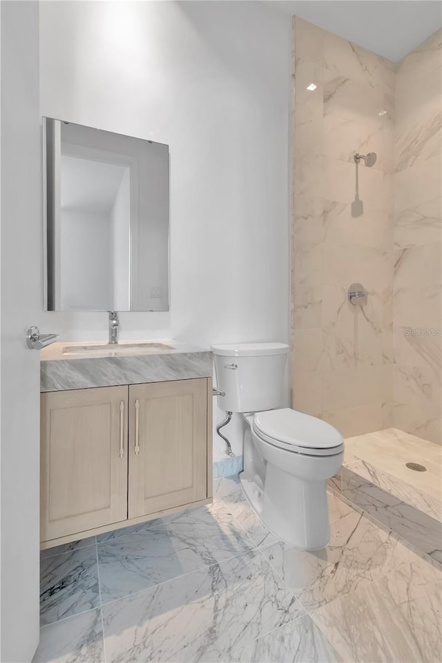 bathroom with tiled shower, vanity, and toilet