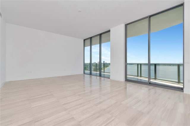 empty room with light wood-type flooring and a wall of windows