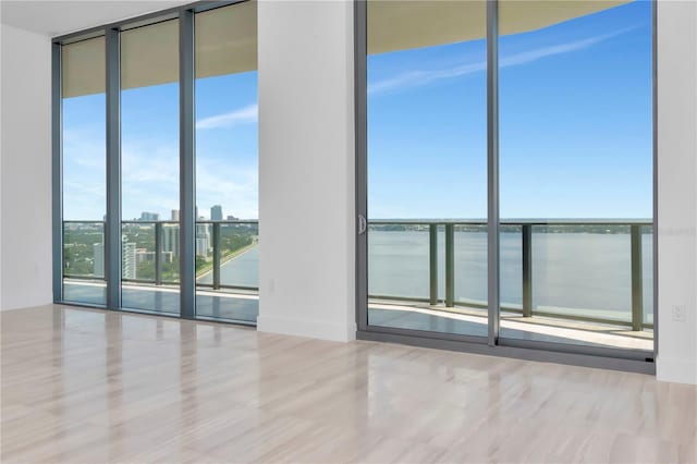 spare room with a water view, floor to ceiling windows, and wood-type flooring