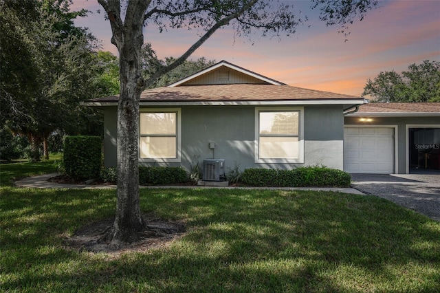 view of front of home with cooling unit, a lawn, and a garage