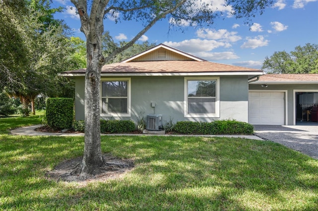 view of front of property featuring a garage, central AC, and a front yard