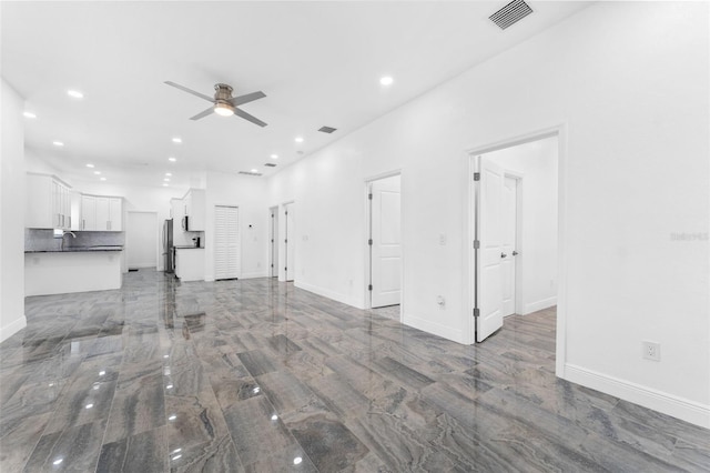 unfurnished living room featuring ceiling fan and sink