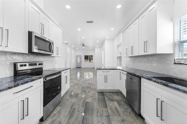 kitchen with dark stone countertops, appliances with stainless steel finishes, white cabinets, and decorative backsplash