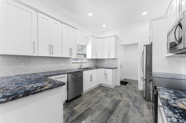 kitchen with white cabinets, dark stone countertops, appliances with stainless steel finishes, sink, and tasteful backsplash