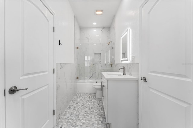 full bathroom featuring tile walls, tiled shower / bath, toilet, and vanity