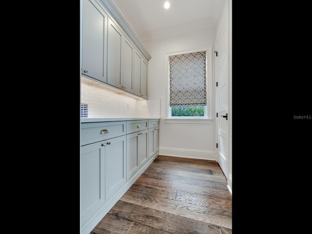 kitchen with crown molding, gray cabinetry, dark hardwood / wood-style flooring, and tasteful backsplash