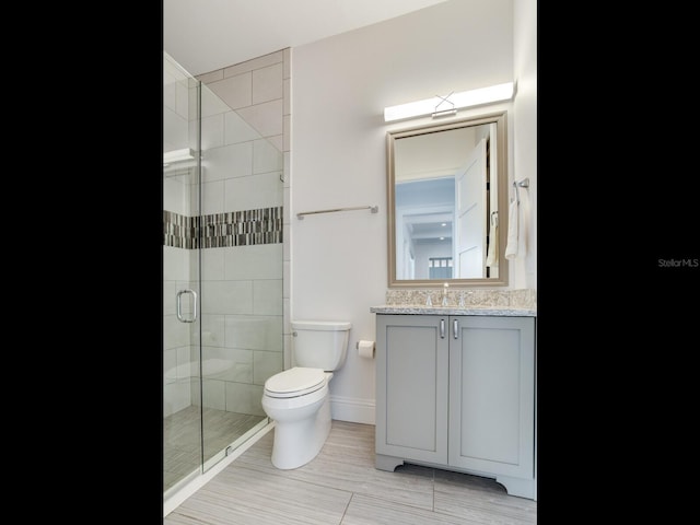 bathroom featuring vanity, a shower with shower door, and toilet