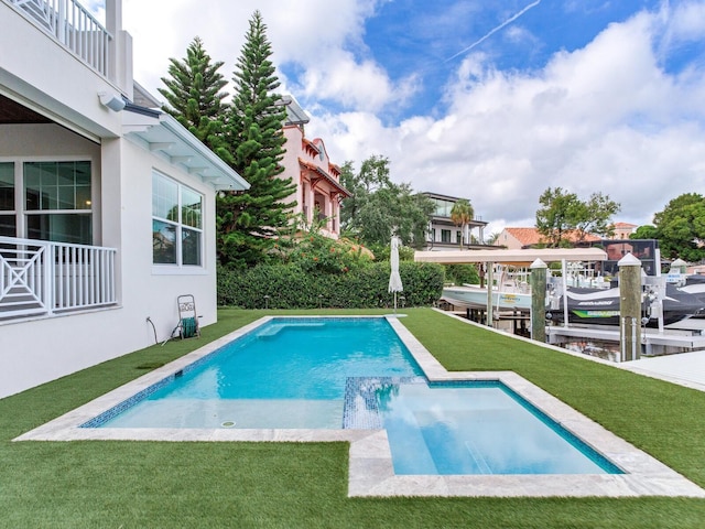 view of pool featuring pool water feature, a boat dock, a patio area, and a yard