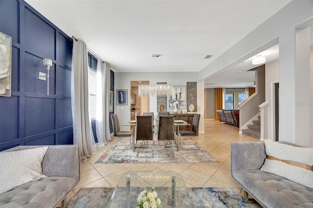 10820 Carloway Hills Dr, Wimauma, FL 33598 - living room with light tile patterned floors, visible vents, stairway, and an inviting chandelier