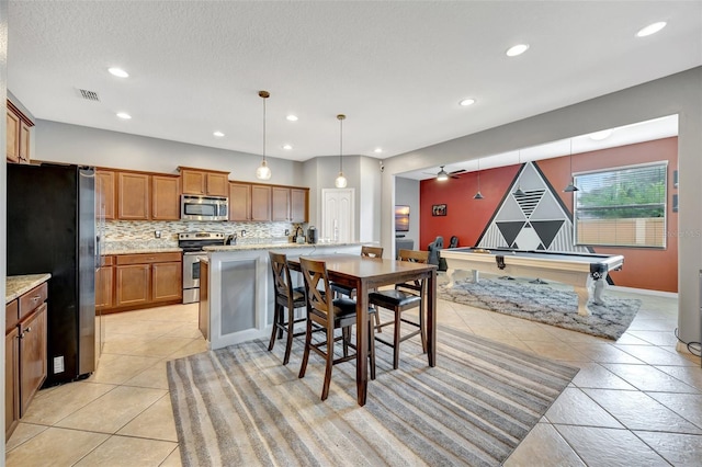 10820 Carloway Hills Dr, Wimauma, FL 33598 - kitchen featuring visible vents, tasteful backsplash, appliances with stainless steel finishes, brown cabinetry, and light tile patterned floors