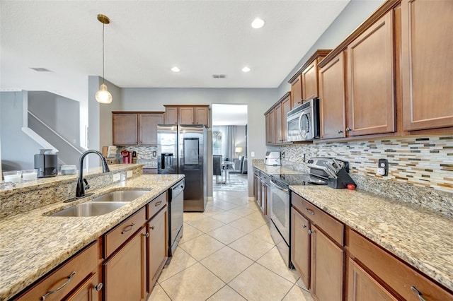 kitchen featuring light stone countertops, hanging light fixtures, stainless steel appliances, sink, and light tile patterned flooring