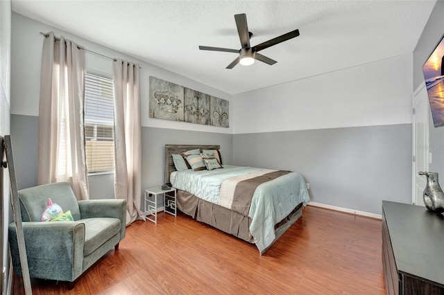 bedroom with a textured ceiling, wood-type flooring, and ceiling fan