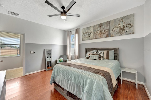 bedroom featuring ceiling fan, wood-type flooring, and a textured ceiling